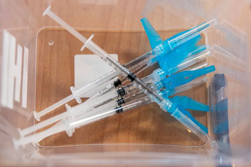 Used syringes collected in a clear plastic medical waste container